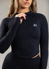 Black long-sleeve athletic top with a logo on a neutral background